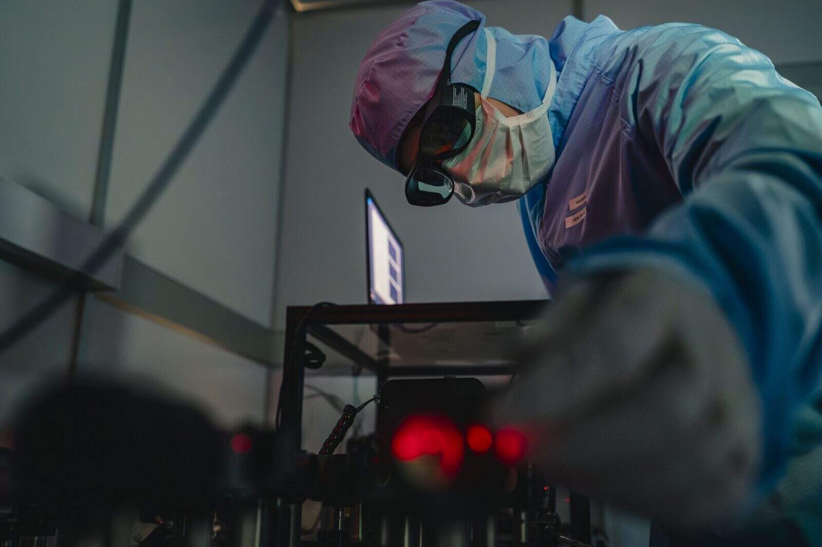 Technician performing laser damage testing with precision equipment.